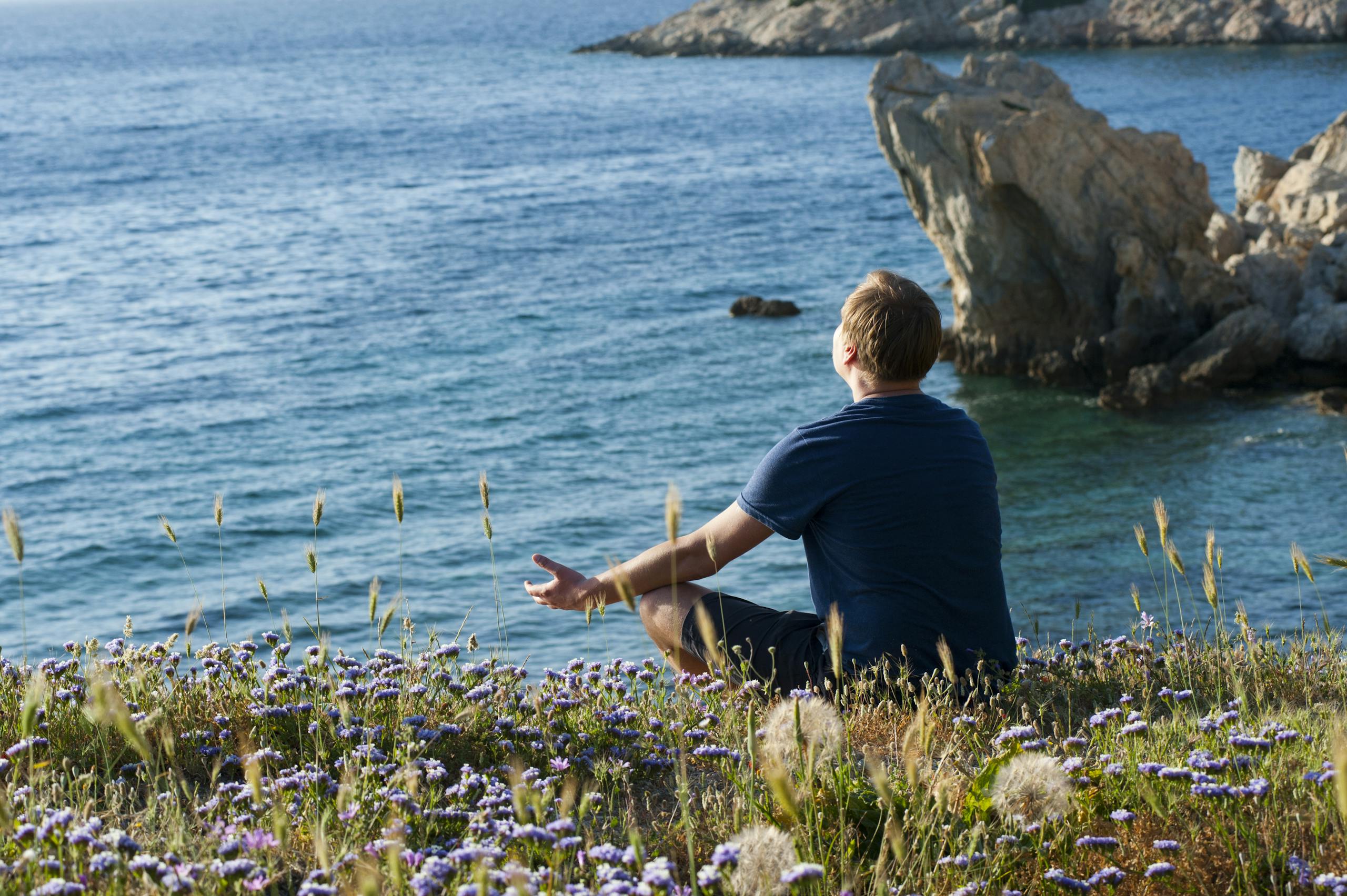 A man enjoys a peaceful moment surrounded by flowers and sea views in Datça, Turkey.